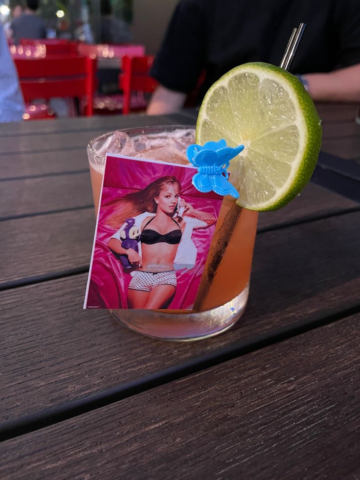 a drink with a lime slice on the rim and a photo pinned to it's side