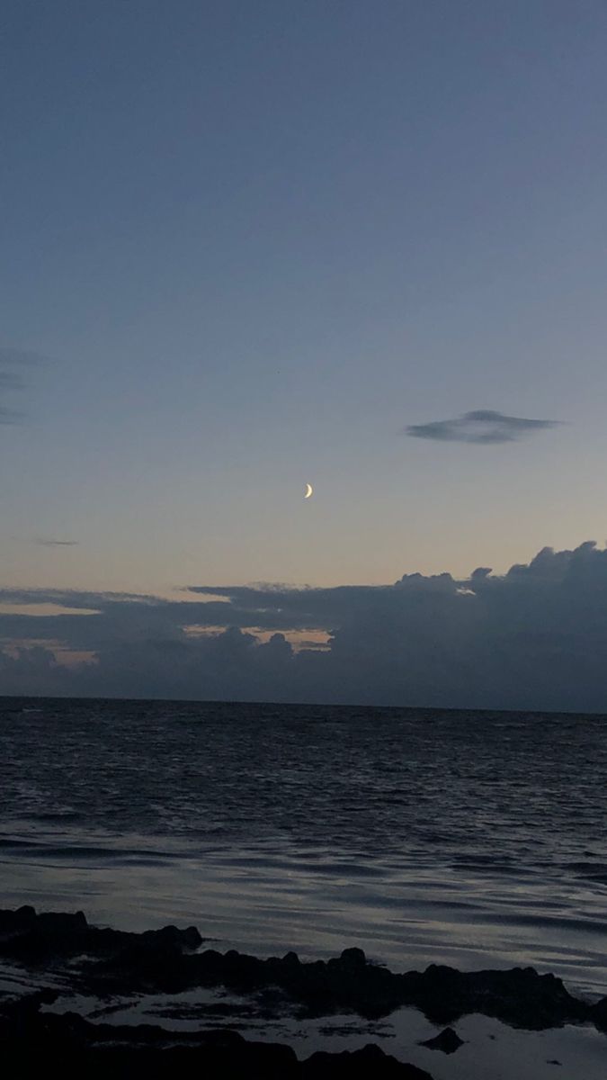 the moon is shining in the sky over the ocean