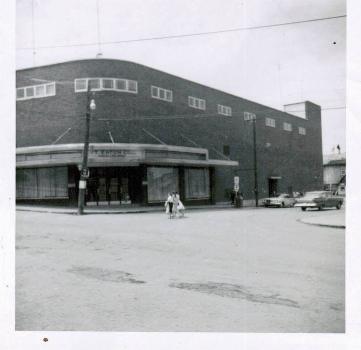 an old black and white photo of two people walking in front of a large building