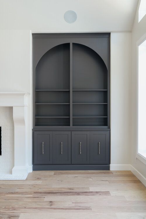 an empty living room with a fireplace and built in bookcases