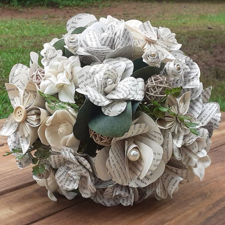 a bridal bouquet made out of old book pages on a wooden table in the grass