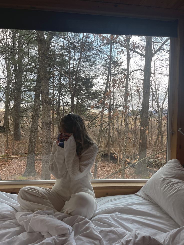 Sitting in front of a window overlooking the woods in winter ny  in a neutral style comfy style cozy winter aesthetic cabin H&M knit sweater and lounge pants very cozy style Cozy Winter Cabin Aesthetic, Cabin In The Woods Aesthetic, Winter Cabin Aesthetic, Cozy Cabin Aesthetic, Aesthetic Cabin, Cozy Winter Aesthetic, Cabin Outfit, Cozy Winter Cabin, Cabin Weekend