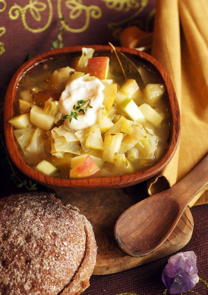 a wooden bowl filled with soup next to bread