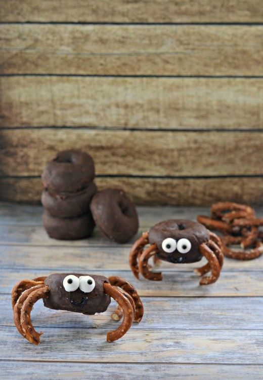 chocolate crab cookies with googly eyes on wooden table next to brown crabs and pretzels