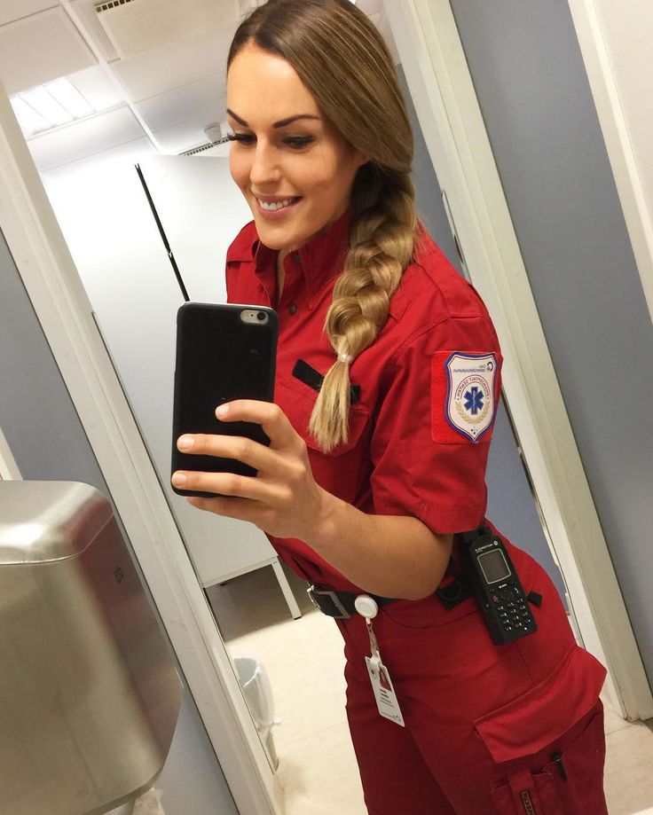 a woman in an orange jumpsuit is looking at her cell phone while standing in front of a mirror