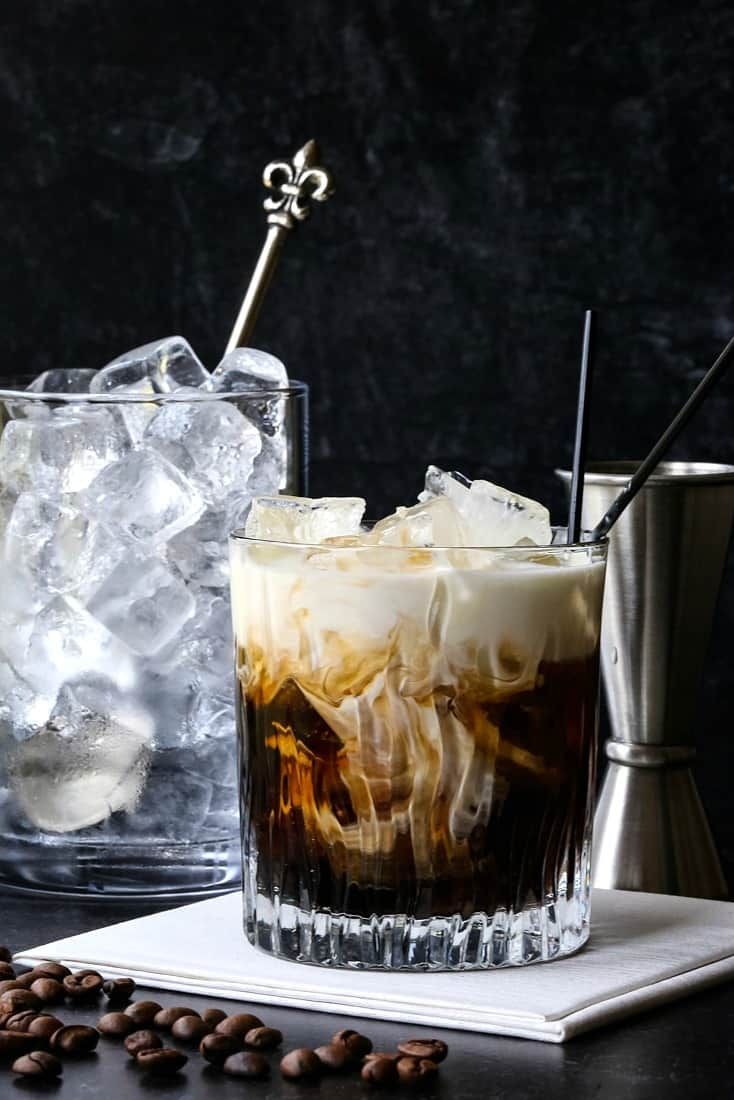 two glasses filled with ice and coffee on top of a table