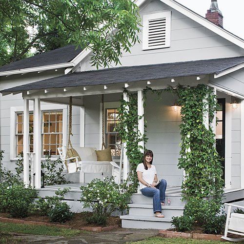 a woman sitting on the front porch of a house with ivy growing all over it