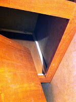 the corner of a wooden cabinet with an open door