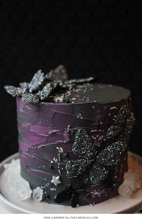 a purple and black cake sitting on top of a white plate