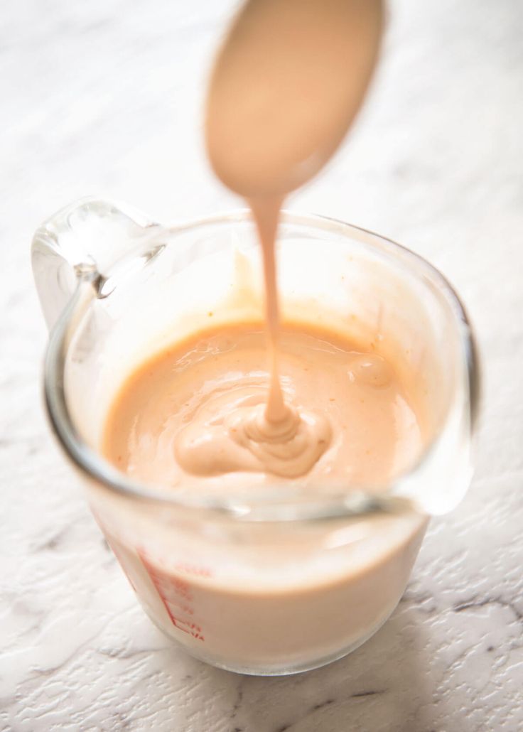 a spoon pouring liquid into a glass cup