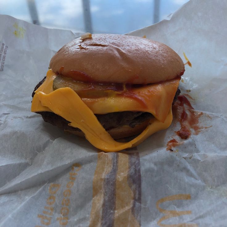 a cheeseburger sitting on top of a piece of wax paper covered in melted cheese