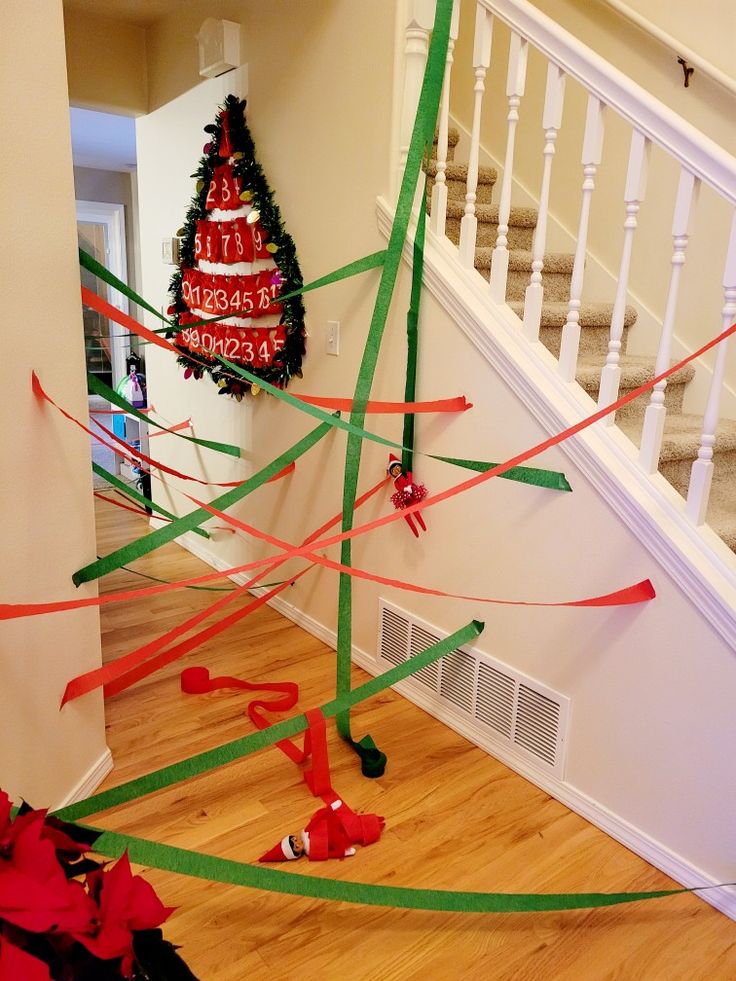 the christmas tree is decorated with ribbons and streamers on the floor in front of the stairs