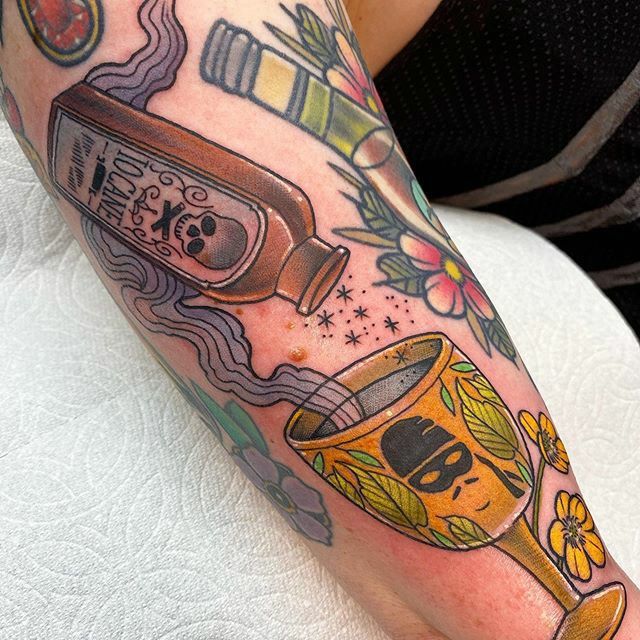 a woman's leg with tattoos on it and an image of a bottle in the middle