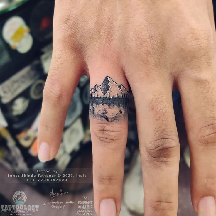 a person's hand with a small tattoo on it and mountains in the background