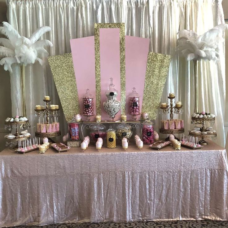 a table topped with lots of desserts and candy covered in pink, gold and white