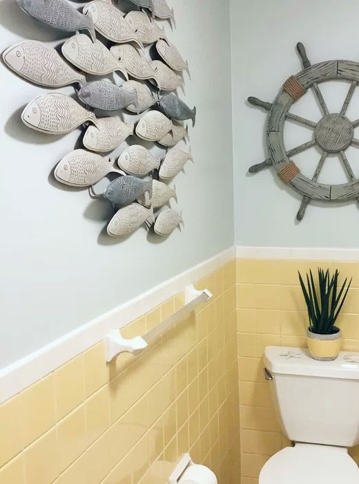 a white toilet sitting in a bathroom next to a wall mounted with fish on it