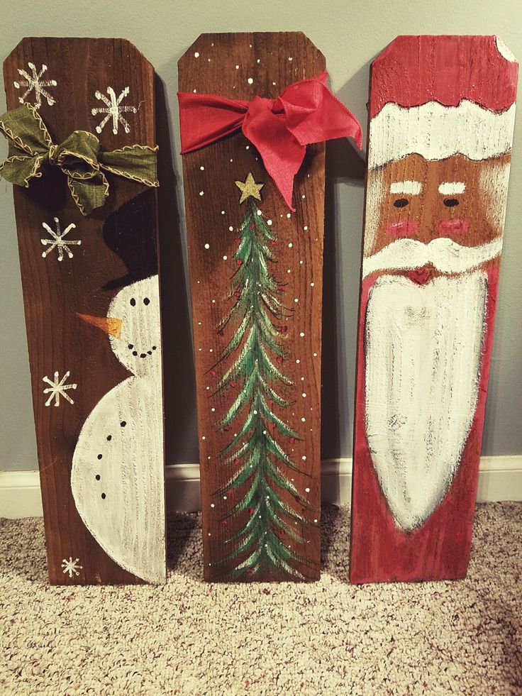 three wooden christmas decorations with santa claus and snowman on them, sitting in front of a wall