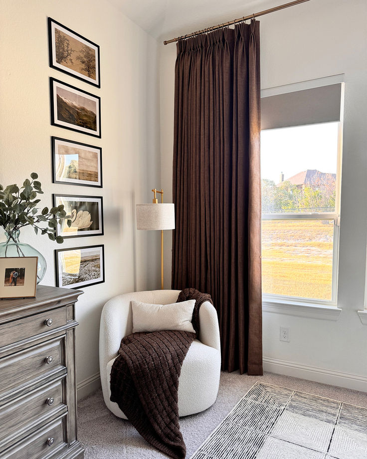 a living room with pictures on the wall and a chair in front of a window