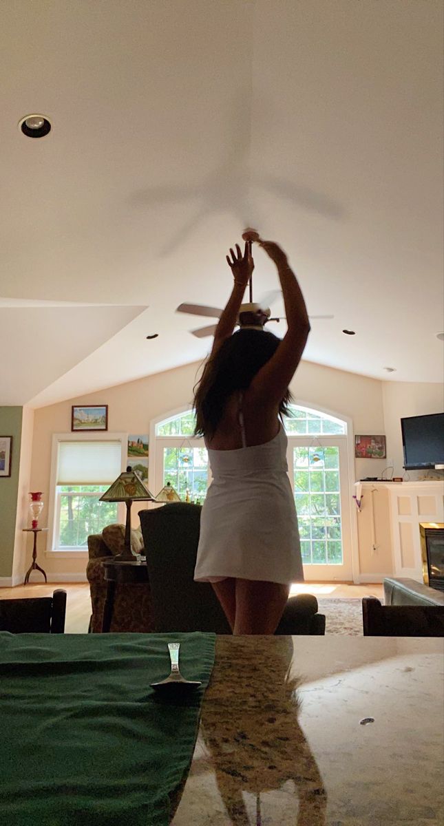 a woman in a white dress reaching up to catch a frisbee with her hands