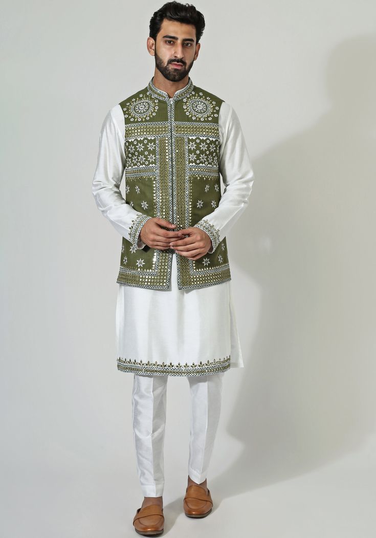 Featuring a stylish green cotton silk nehru jacket, intricately enriched with mirror and thread embroidery. Complemented by an off-white mirror work embellished cotton silk kurta and coordinating pants. A perfect choice for setting the stage on fire at any sangeet celebration.Composition : Nehru, Kurta and Pants - Cotton SilkCare: Dry Clean Only and Vacuum Storage This product can be customized for sleeves, length of blouse and neckline Delivery : 3-4 weeks as the product is hand crafted. Check Size Guide or choose MySize for free customisation (All Sizes above XL can be made at 15% additional cost) For more information and sizes please contact fabiliciousfashion@gmail.com or visit our Copenhagen studio. About the Designer : Chatenya Mittal started his career with a degree in Fashion from Cotton Nehru Jacket With Chikankari Embroidery For Eid, Eid Cotton Nehru Jacket With Chikankari Embroidery, Eid Cotton Nehru Jacket With Zari Work, Cotton Bollywood Nehru Jacket For Festive Occasions, White Bollywood Style Cotton Nehru Jacket, White Bollywood Style Nehru Jacket, Green Sherwani With Mirror Work For Festive Occasions, Festive Green Sherwani With Mirror Work, Green Cotton Sherwani With Zari Work