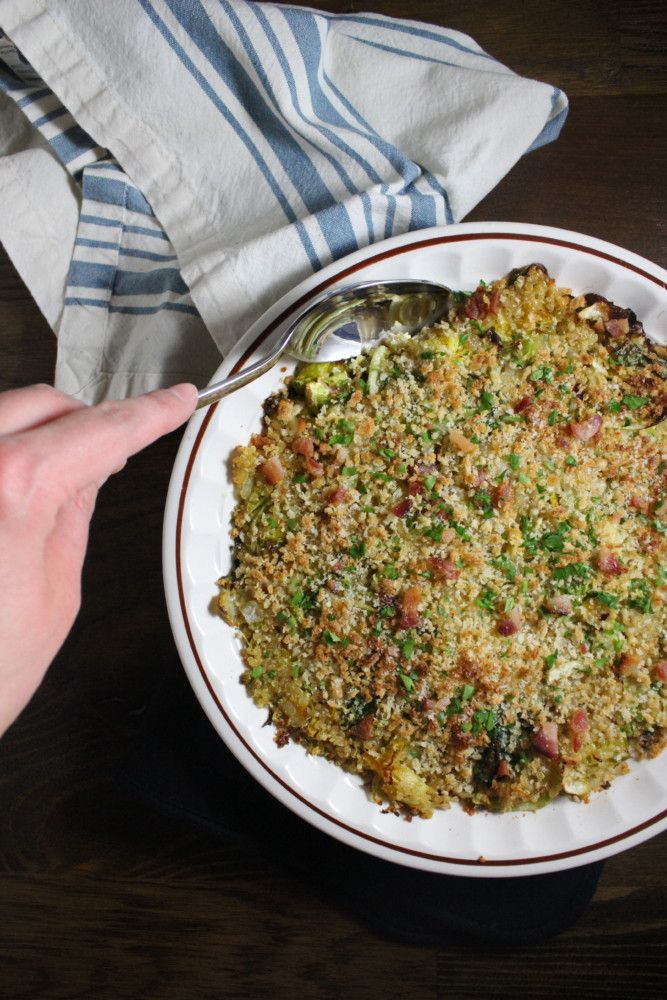 a white plate topped with food on top of a wooden table next to a person's hand