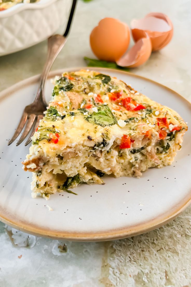 a slice of quiche on a plate with an egg in the background