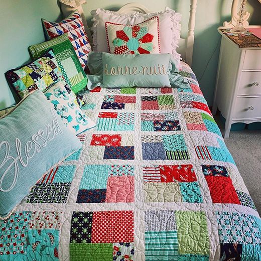 a bed with colorful quilts and pillows on it