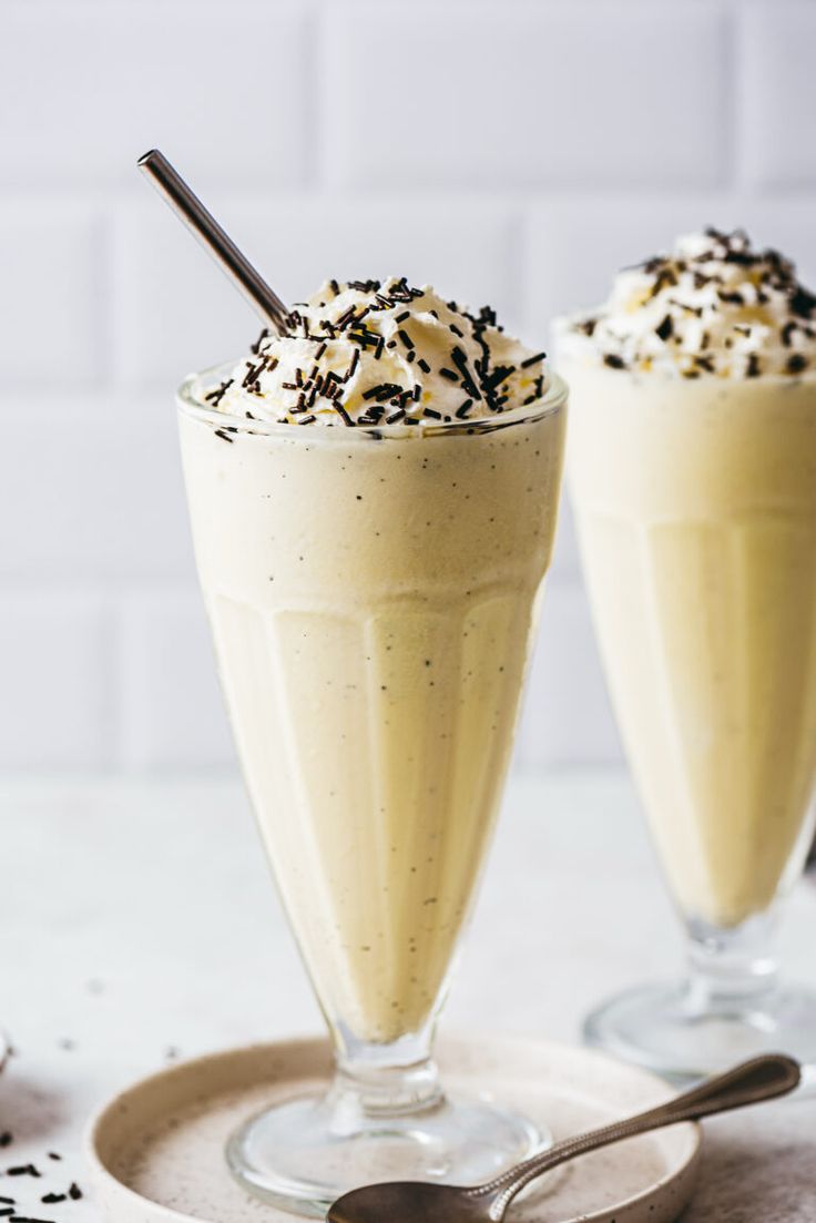 two glasses filled with ice cream and topped with sprinkles on a plate