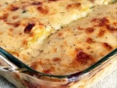 a casserole dish with cheese and meat in it sitting on a white cloth