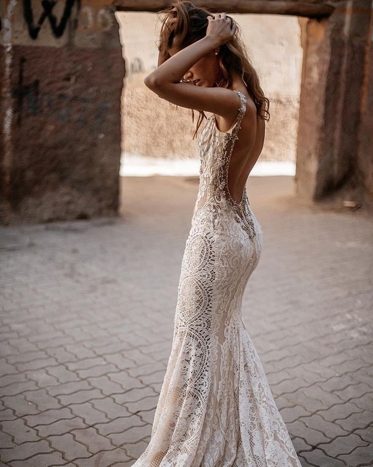 a woman in a wedding dress standing on a brick floor with her arms behind her head