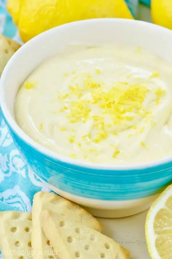 a bowl of dip with lemons and crackers