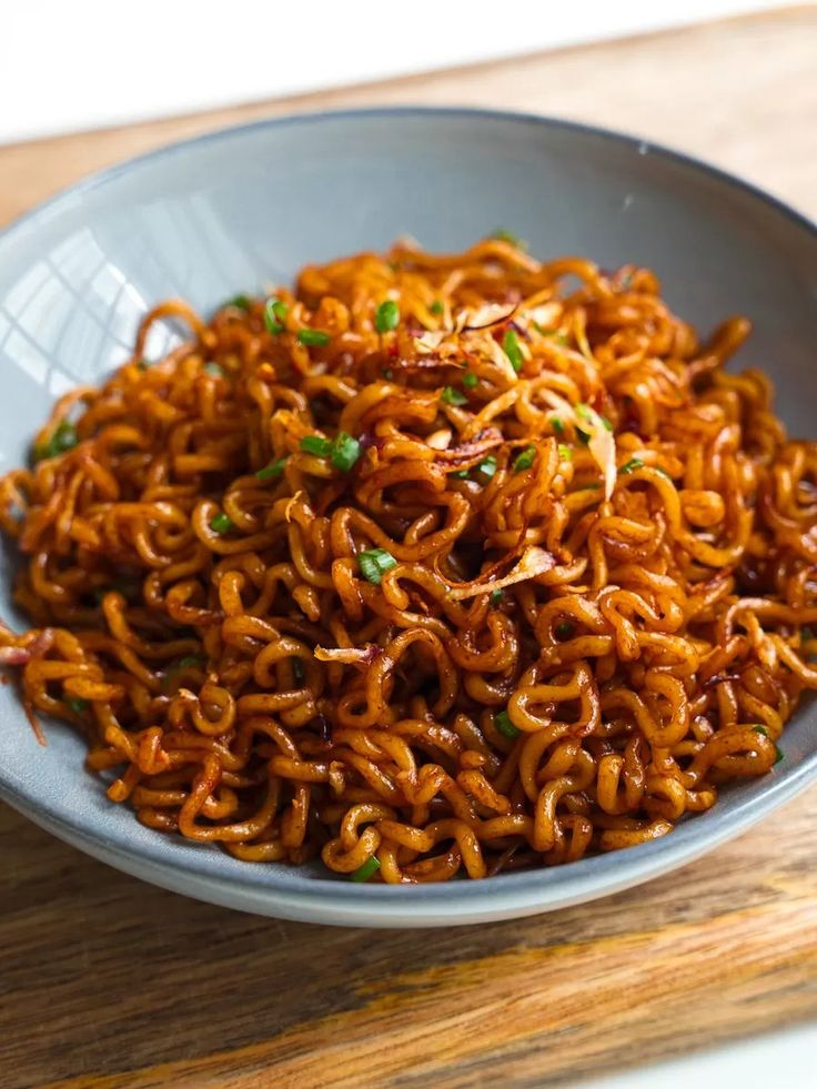 a bowl filled with noodles on top of a wooden table