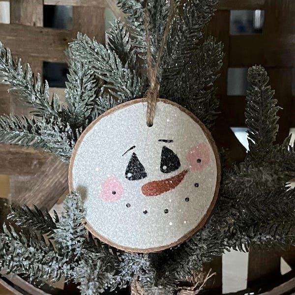 a snowman ornament hanging from a christmas tree