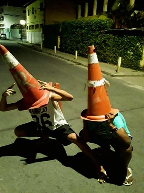 two young men playing with traffic cones on the street