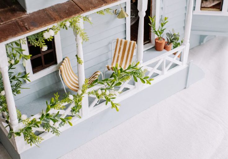 a doll house with chairs and plants on the balcony