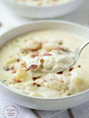 a spoonful of potato soup with bacon and cream in a white bowl on a table