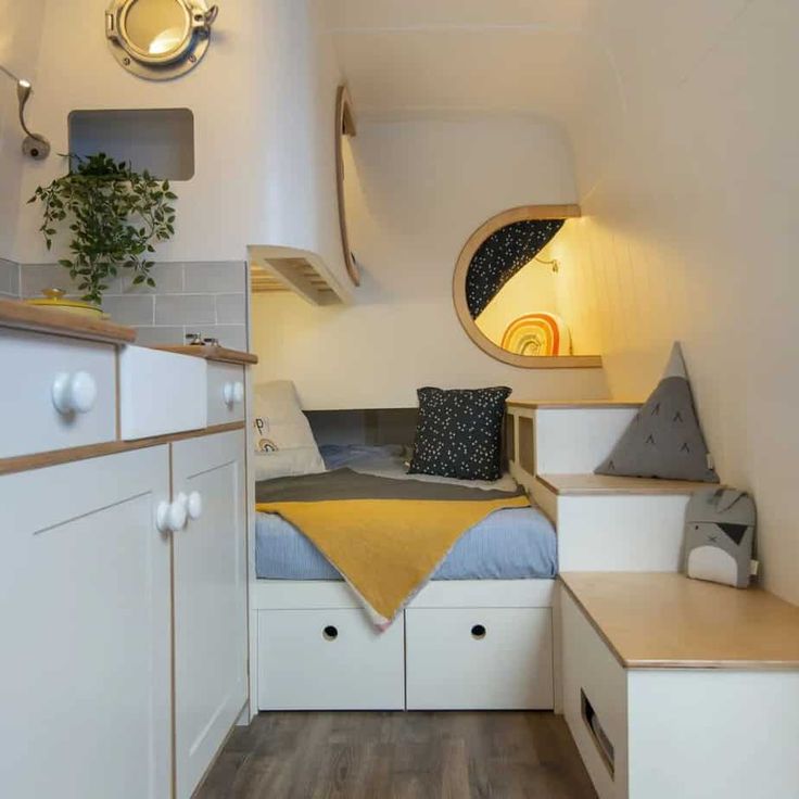 a small bedroom with white cabinets and drawers