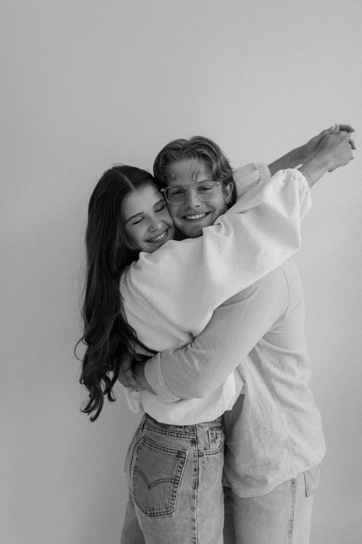 black and white photograph of two women hugging each other in front of a wall with one woman's arms around the other