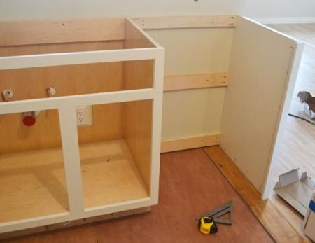 an unfinished kitchen cabinet with tools on the floor