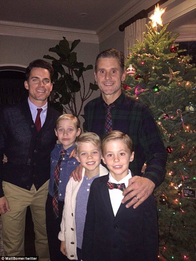 a group of people standing next to each other in front of a decorated christmas tree