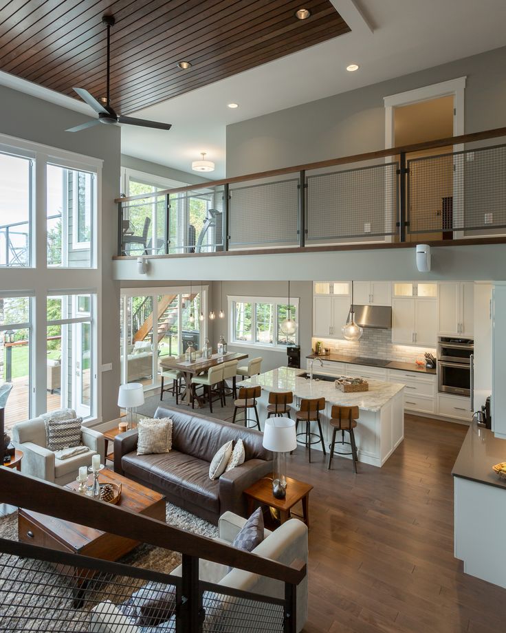 a living room filled with furniture next to a kitchen and dining room table in front of large windows