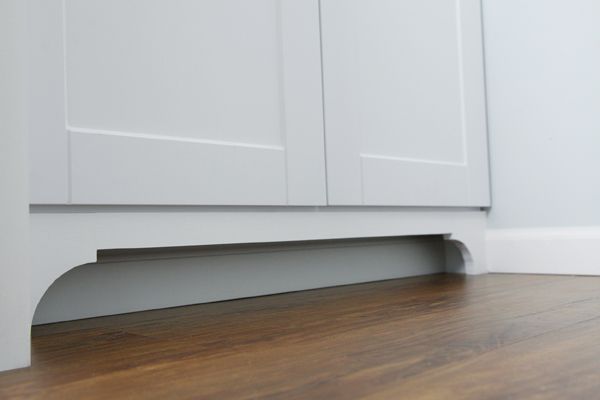 an empty kitchen with white cabinets and wood flooring