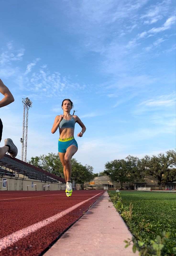 a woman running on a track with another person in the background