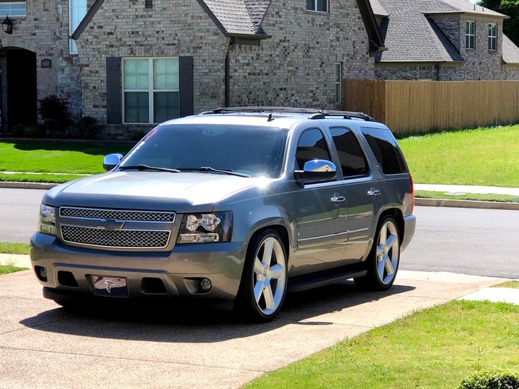 a silver suv parked in front of a house on the side of a street with grass