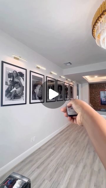 a person holding up a cell phone in front of a wall with pictures on it