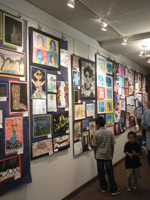 a group of people standing next to each other near a wall covered in pictures