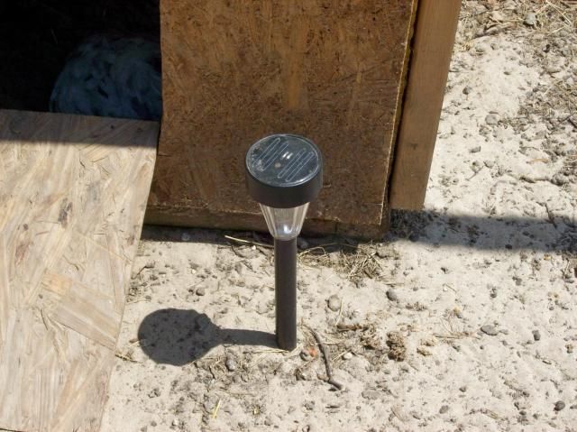 a parking meter sitting on the side of a road next to a wooden door and plywood