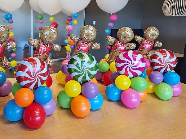 some very pretty colorful candy candies on a table with balloons in the shape of bears