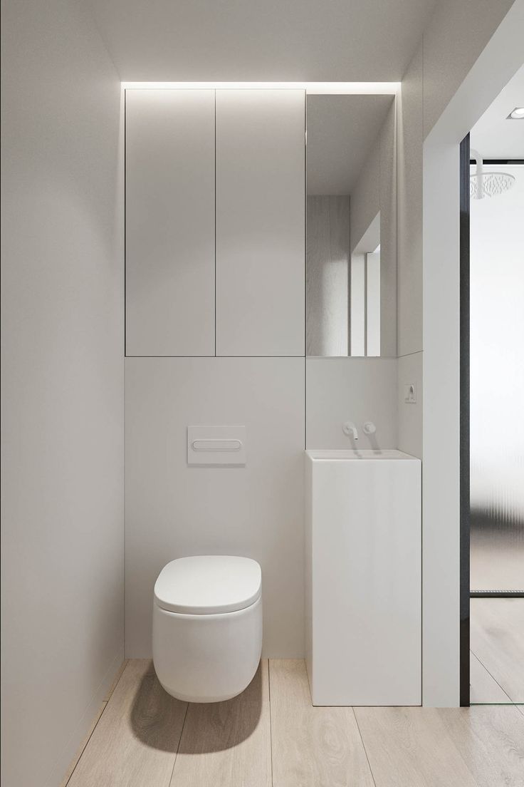 a white toilet sitting in the middle of a bathroom next to a wall mounted cabinet