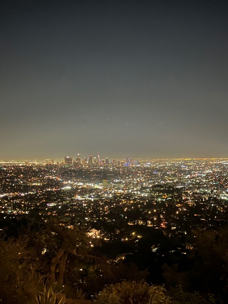 the city lights shine brightly at night from atop a hill in los angeles, california